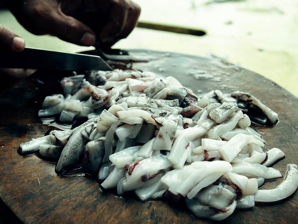 A closeup of cut squid ready to be used as bait for fishing on a wooden table top