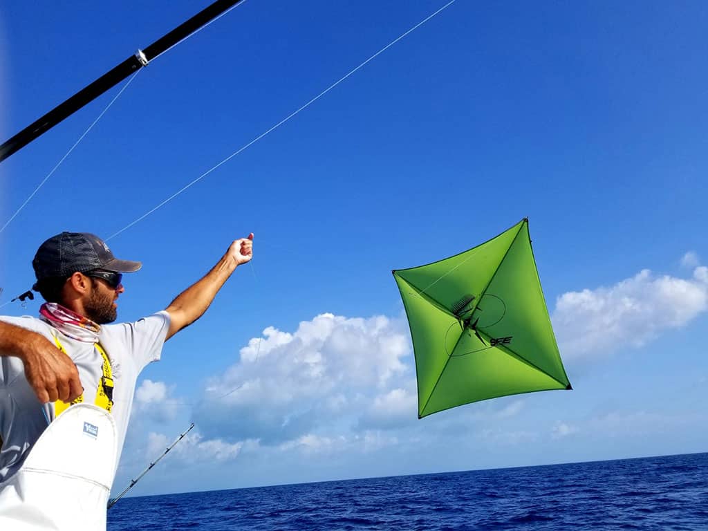 An angler tries to lure a fish offshore by kite fishing with a green kite