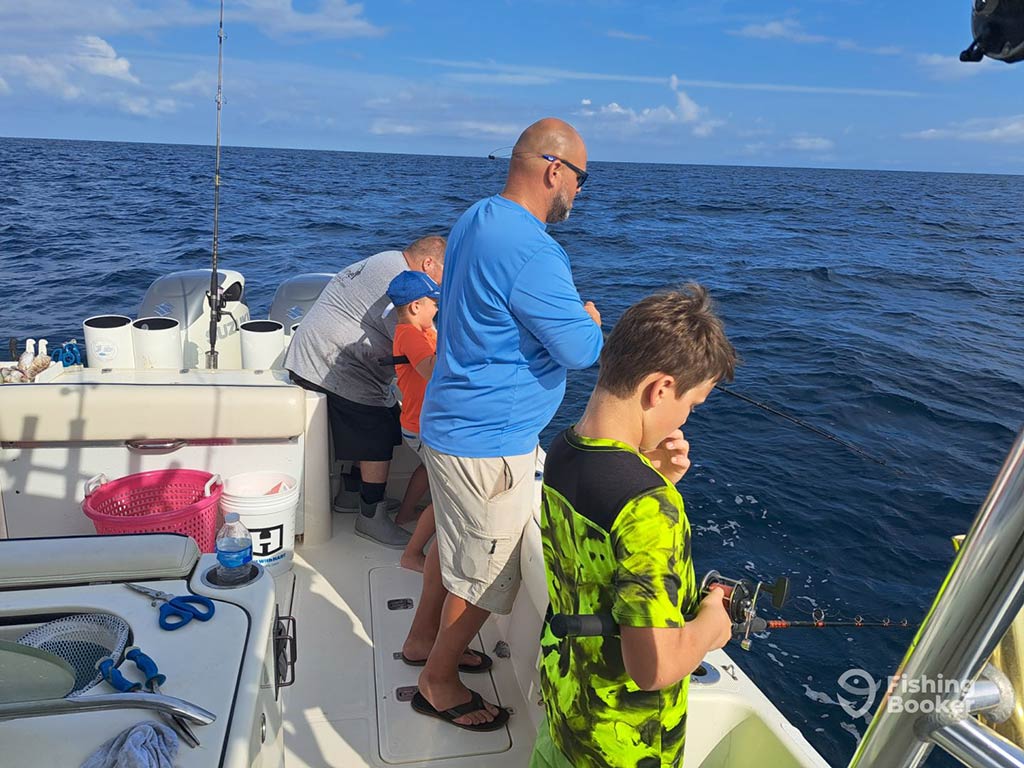 Two men and two young boys fish over the side of a deep sea fishing charter out of Panama Beach on a sunny day